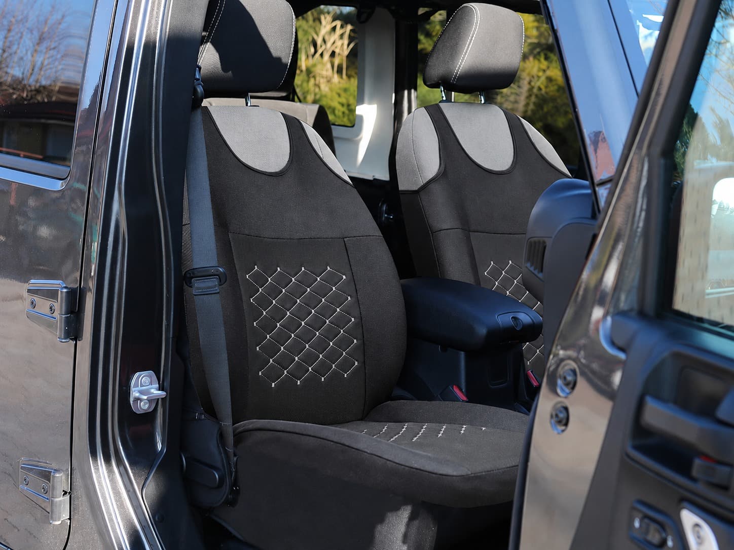 Housses de siège auto type T-shirt Motive noires avec surpiqûres grises installées sur les sièges avant d’une voiture