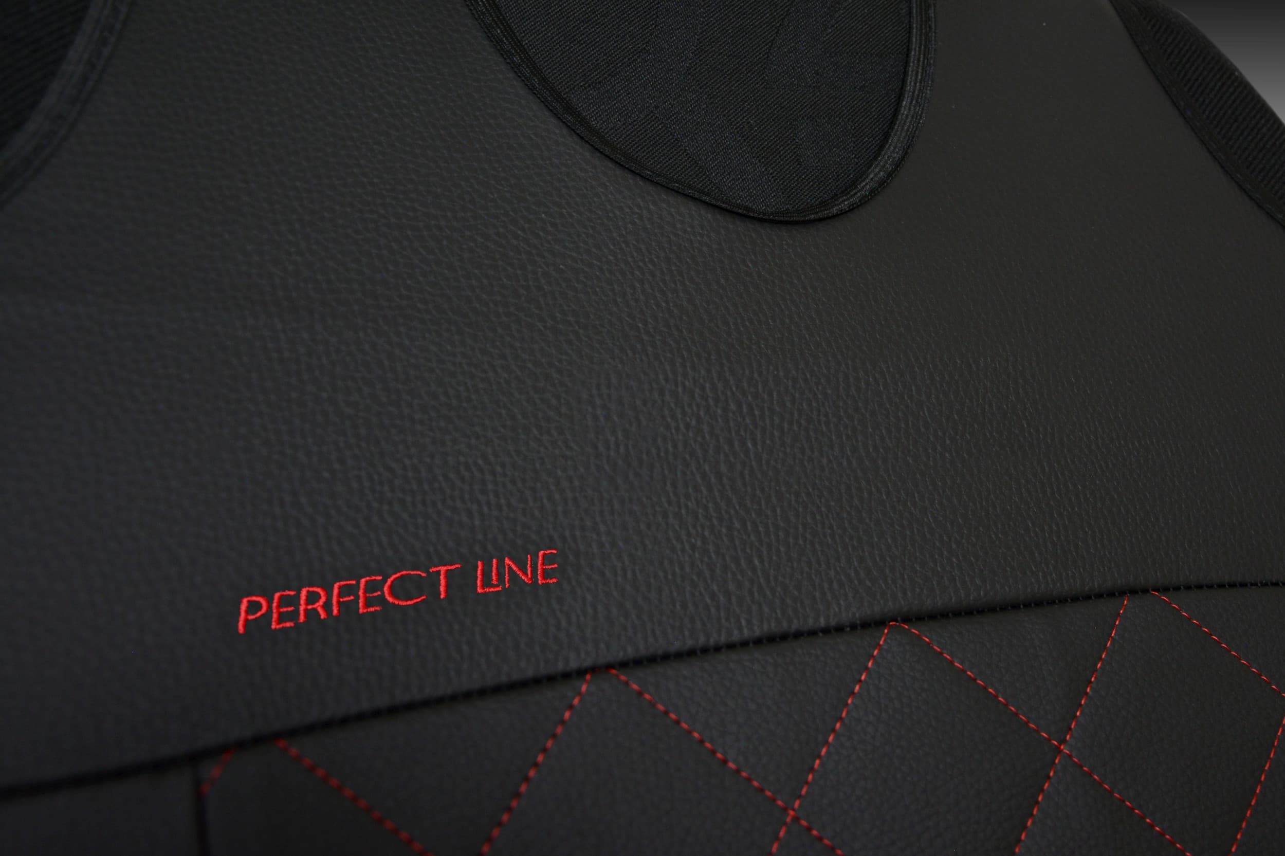 Détail de la broderie et des coutures sur simili cuir rouge